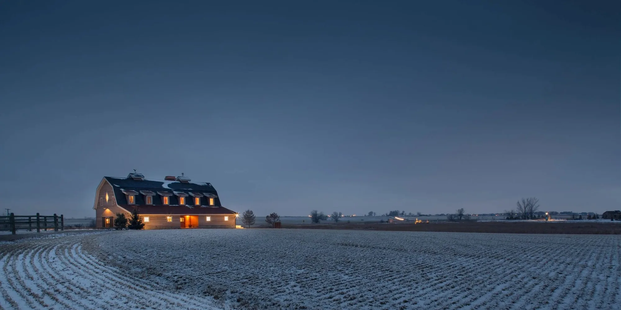 A Frameworks home lit at night across an open field