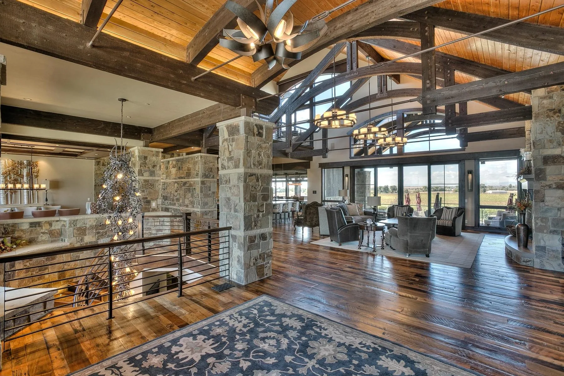 A great room under heavy timber trusses with stone columns and a wood floor